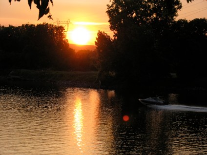 a motor boat at sunset speeds by the Isle of the Cayugas in the Mohawk River behind Washington Ave in Schenectady NY - 27May2010